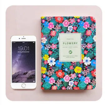 Green floral notepad with fabric imitation leather cover lying open on a table.
