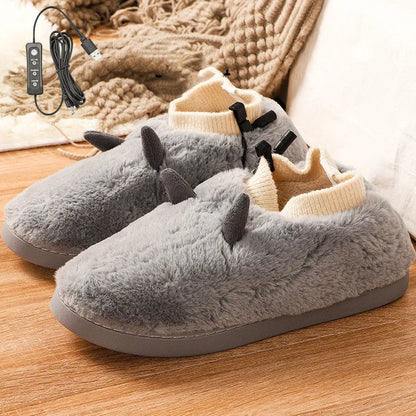 USB heating slippers in black plugged into a laptop, showing the cable and soft velvet upper.