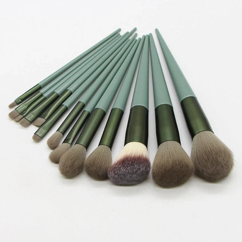 13 green makeup brushes with plastic handles and aluminium ferrules arranged with storage bag