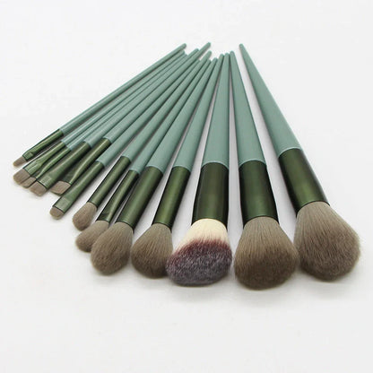 13 green makeup brushes with plastic handles and aluminium ferrules arranged with storage bag