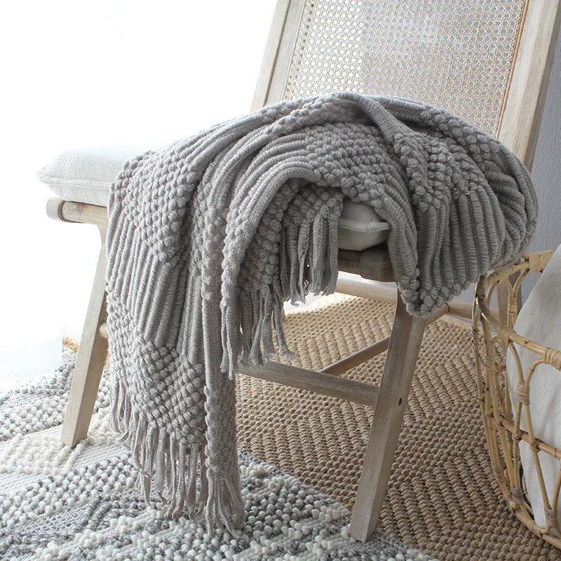 Nordic style knitted bubble texture blanket in light grey, draped over a sofa.