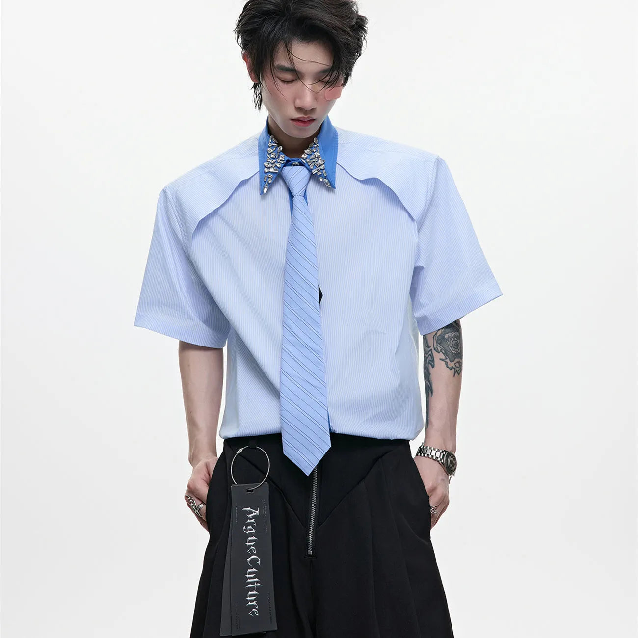 Man wearing a blue loose fit men's shirt with a diamond tie collar and patchwork striped design.