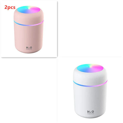 Pink USB desktop humidifier with LED lights and water tank on wooden desk