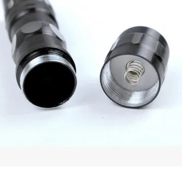 Black aluminium mini LED flashlight shown next to a AA battery for scale.