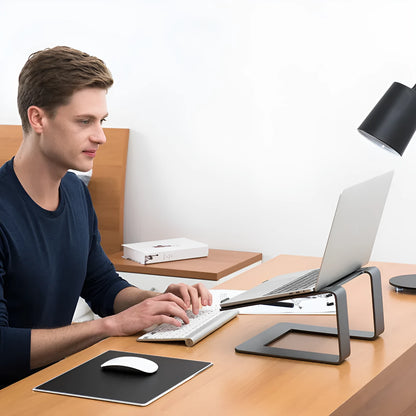 Black aluminium alloy laptop stand on a desk, showing its raised platform and open base design.