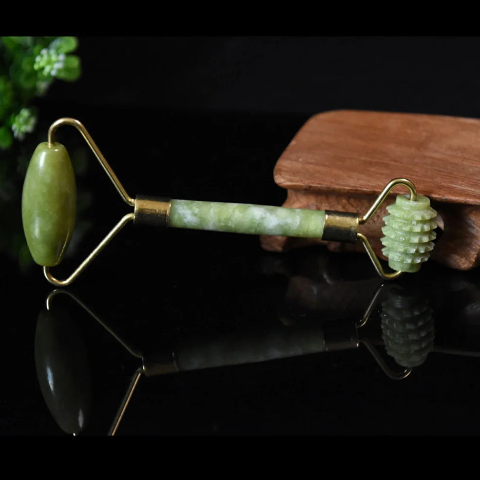 Natural green jade beauty massager with roller and scraper tools on white background
