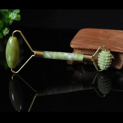 Natural green jade beauty massager with roller and scraper tools on white background