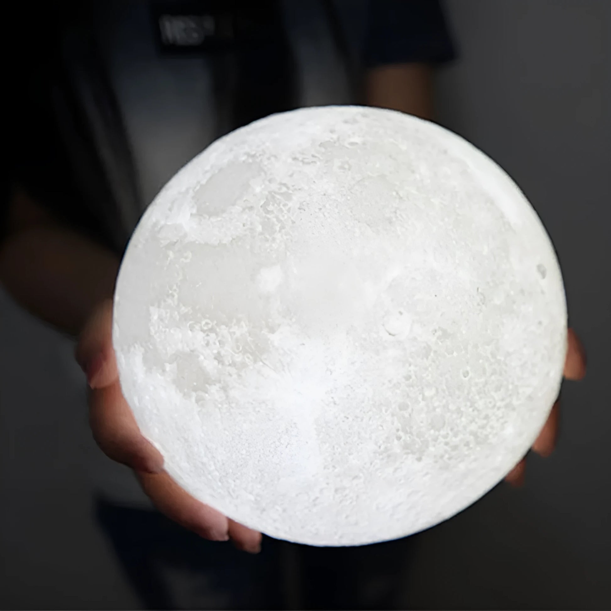 3D printed white moon lamp on a wooden holder, showing detailed crater texture and soft LED glow.