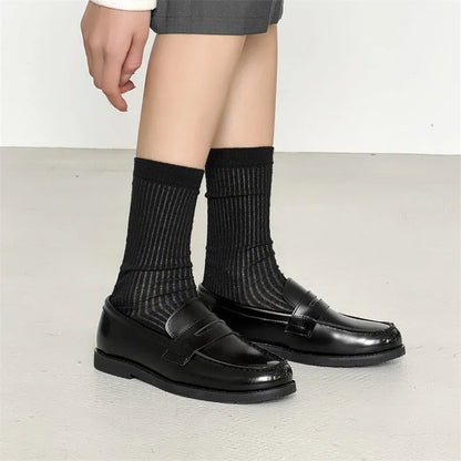 Classic black slip-on Derby leather shoes for men and women on a plain background