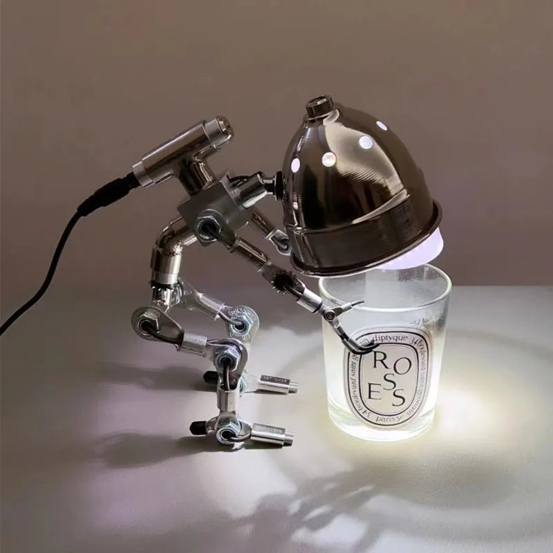 Silver copper robot-shaped decorative desk lamp with custom graphic option on a wooden shelf.