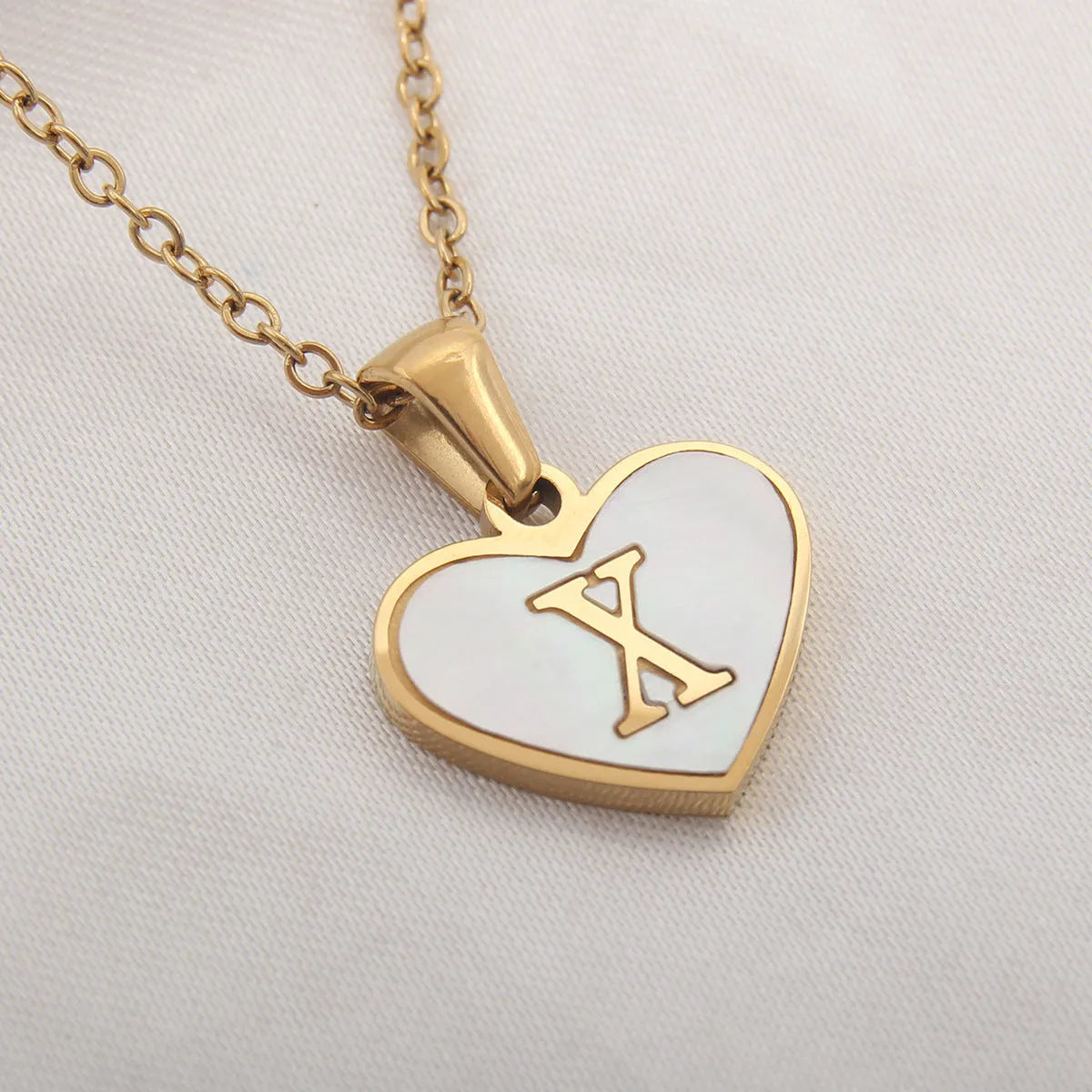 Gold-plated heart necklace with white shell pendant showing letter personalisation option