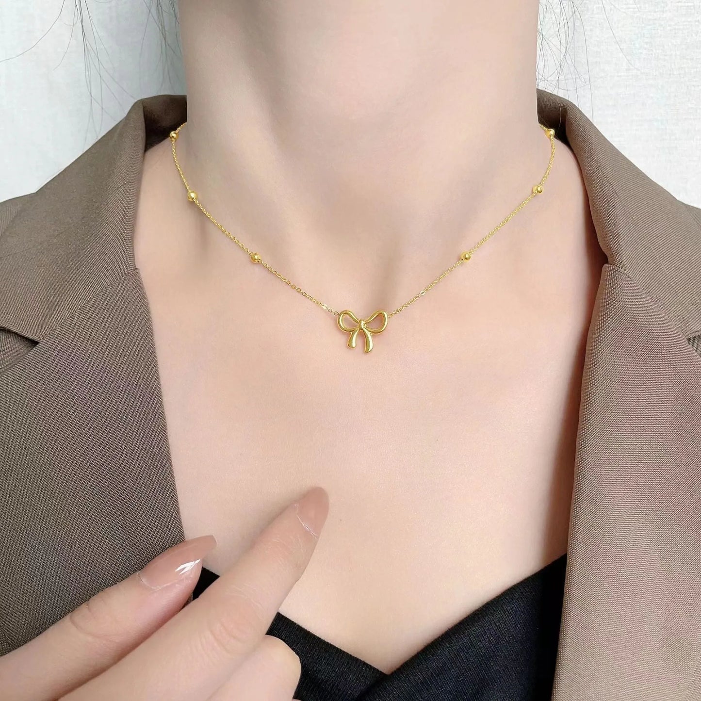 Gold adjustable bow necklace on a cross-link chain, showing the detailed pendant and clasp.