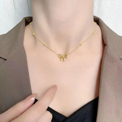 Gold adjustable bow necklace on a cross-link chain, showing the detailed pendant and clasp.