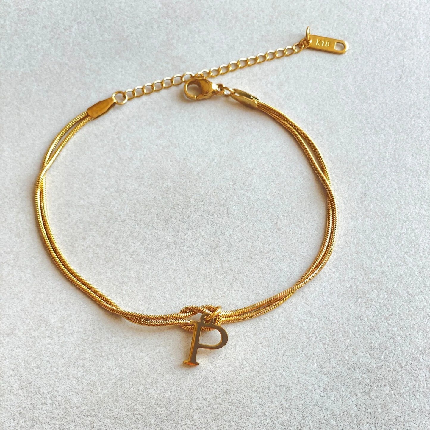 Elegant letter charm bracelets for women in gold and silver tones, featuring a delicate snake chain design and personalised letter charms.