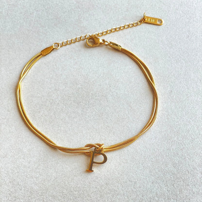 Elegant letter charm bracelets for women in gold and silver tones, featuring a delicate snake chain design and personalised letter charms.