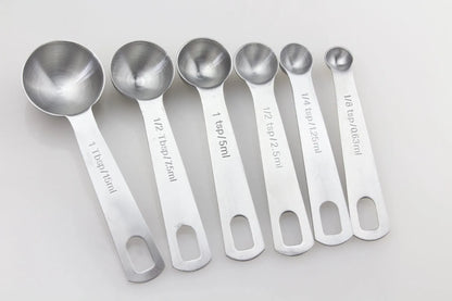 Set of six stainless steel measuring spoons connected by a silver D-ring, showing engraved measurement markings