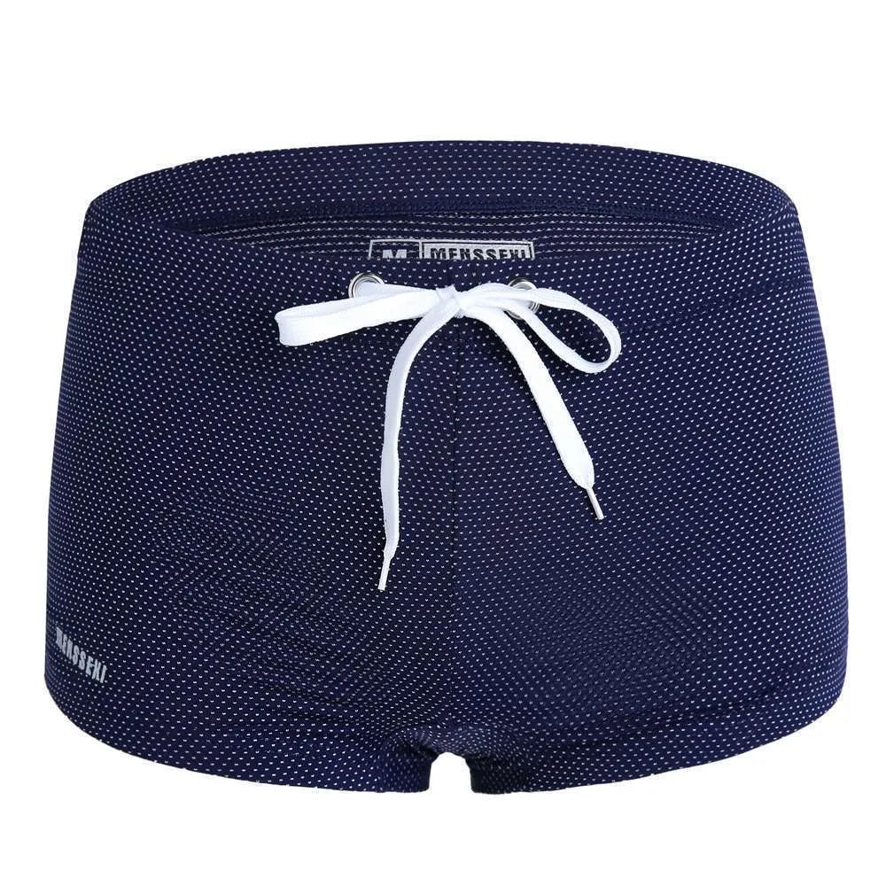 Men's low waist swim trunks in stretch nylon on a man, showing elastic waistband and boxer-style cut.