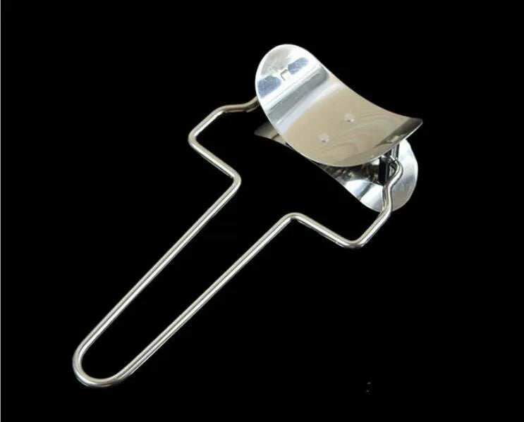 Stainless steel dumpling mould and rectangular dough cutter on a kitchen surface.