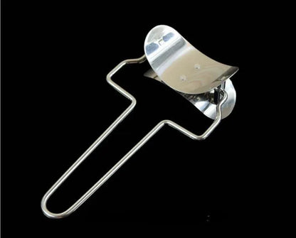 Stainless steel dumpling mould and rectangular dough cutter on a kitchen surface.