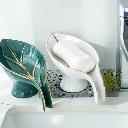 A ceramic soap dish with a sleek leaf-shaped design, featuring a suction cup base for secure and tidy placement in the bathroom or kitchen.
