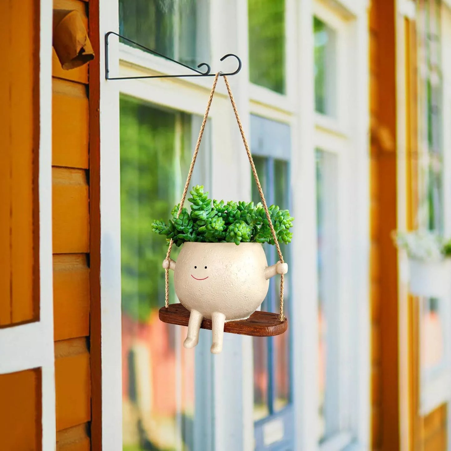 Swing face hanging flower pot with child's smiling design, made of durable resin