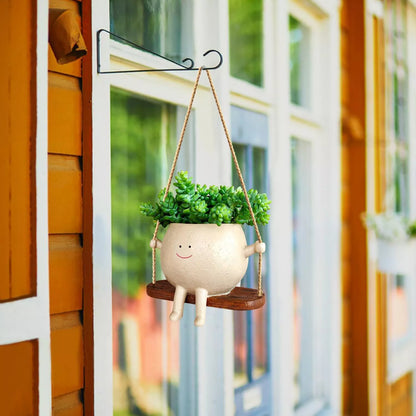 Swing face hanging flower pot with child's smiling design, made of durable resin