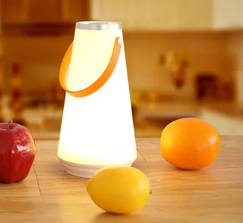 White rechargeable LED lantern with USB cable on a bedside table.