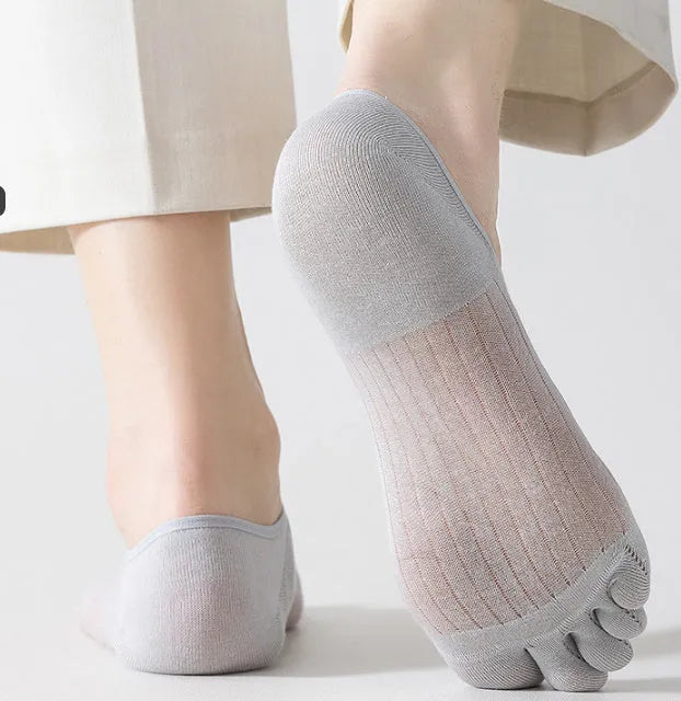 Pair of solid colour modal five-finger invisible socks on a wooden surface, showing toe separation and low-cut design.