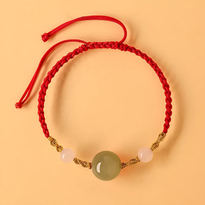 Hand-woven red rope bracelet with Hetian jade lucky beads on a wrist.