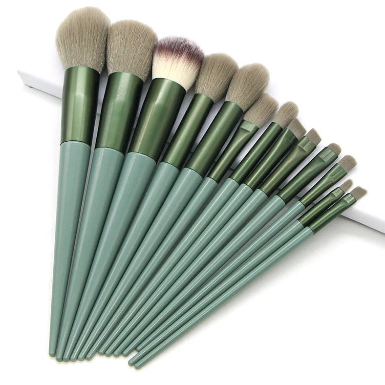 13 green makeup brushes with plastic handles and aluminium ferrules arranged with storage bag