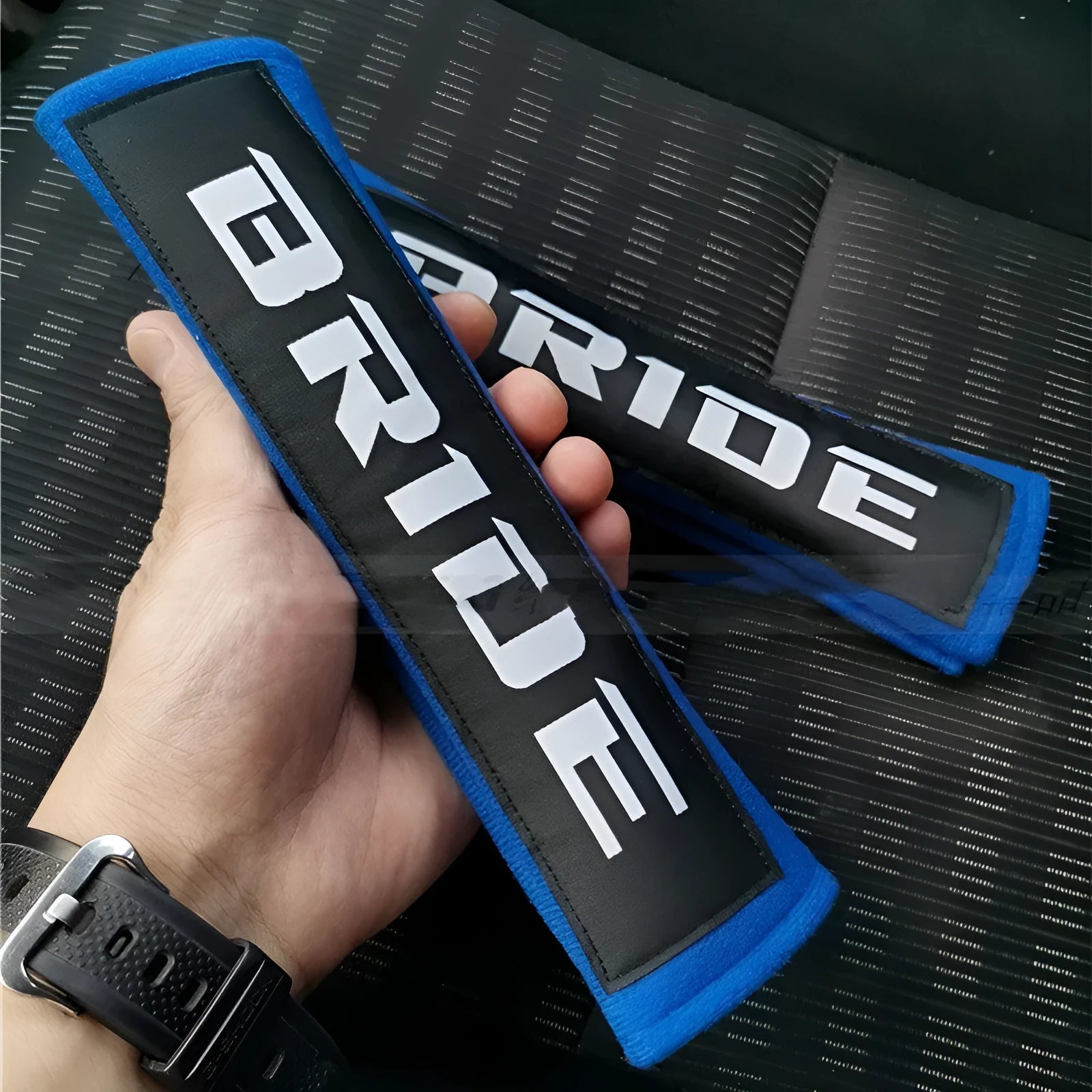Car seat belt shoulder pad protectors in black, blue, and red colours with embroidered woven detailing