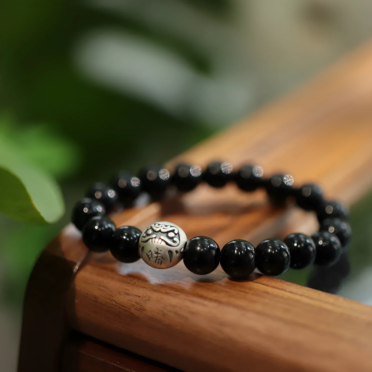 Close-up of a women's black agate bracelet with 10mm beads and a sterling silver clasp on a wrist.