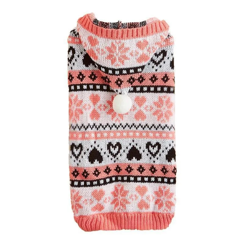 Small dog wearing a pink camouflage patterned knitted sweater with snowflake and heart stripes.