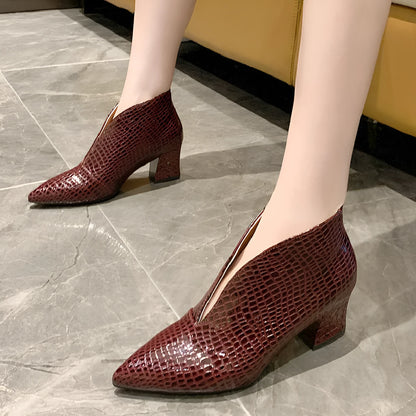 Women's black V cut Martin boots with a pointed embossed toe and a chunky heel.