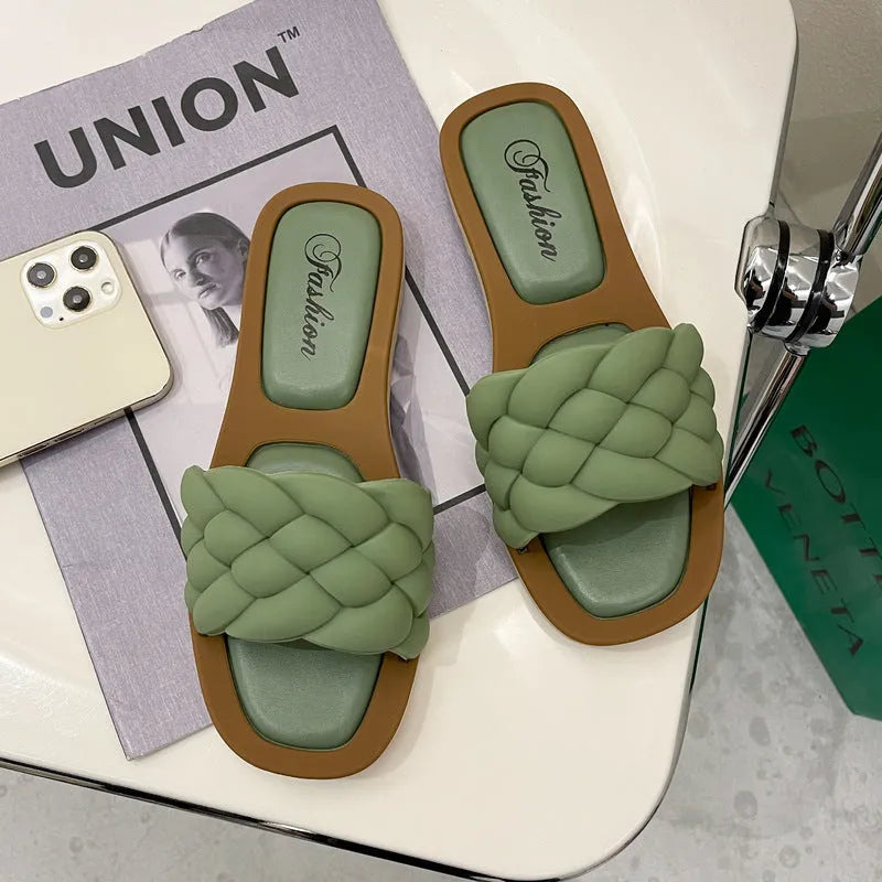 Women's white PVC beach sandals with a thick, patterned sole on a sandy background.