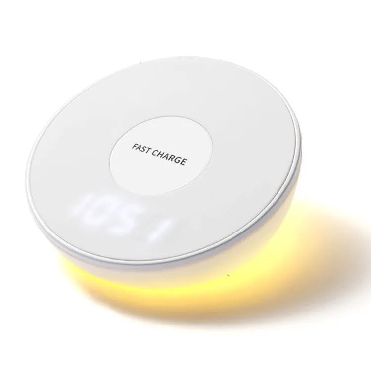 White wireless charging pad with digital clock display and three control buttons on a bedside table.