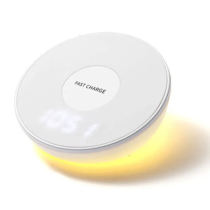 White wireless charging pad with digital clock display and three control buttons on a bedside table.