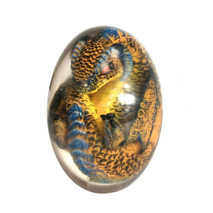 A lifelike resin dragon egg ornament with a crystal-clear, transparent design, sitting on a glowing lava-style base.