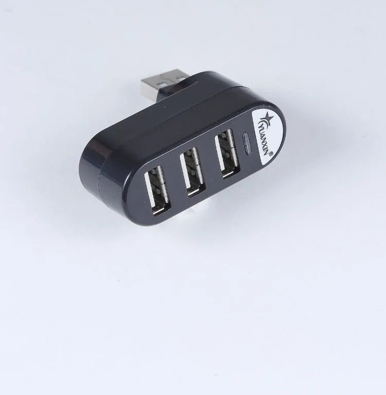 Black and white USB 2.0 hub splitter with spin colour casing on a desk next to a laptop.