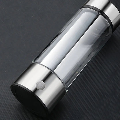Portable hydrogen water bottle with glass chamber and stainless steel components showing electrolysis bubbles