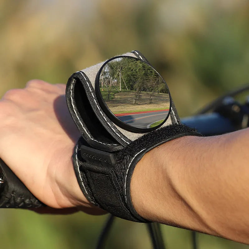 Black nylon bicycle rear-view mirror mounted on a cyclist's wrist.