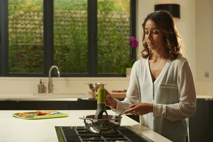 Uutensil Stirr automatic pot stirrer in grey placed inside a saucepan stirring sauce.