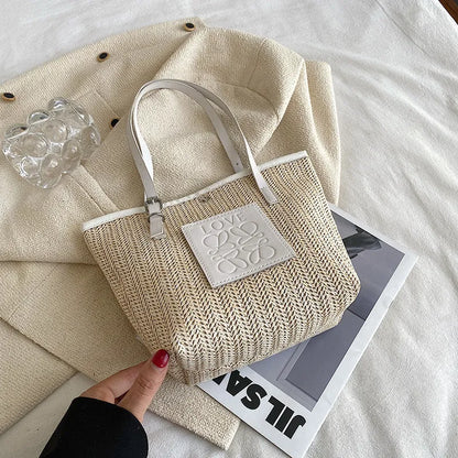White woven straw women's shoulder bag with a three-dimensional pocket and a black handle.
