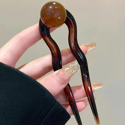 A set of U-shaped acrylic hair barrettes with a simple ball decoration in beige, caramel, and dark grey colours.