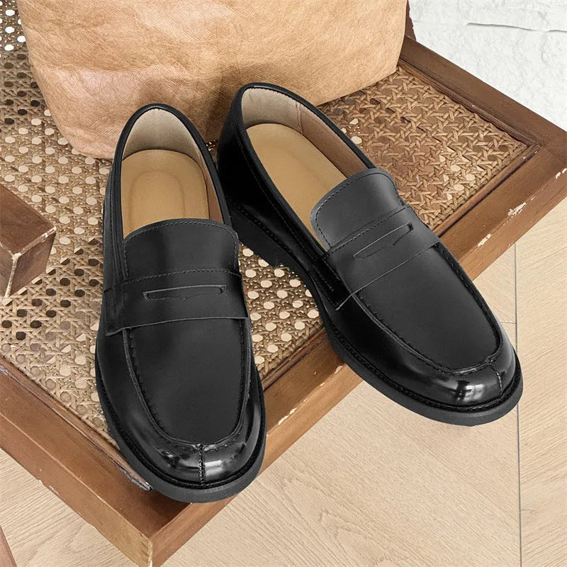 Classic black slip-on Derby leather shoes for men and women on a plain background