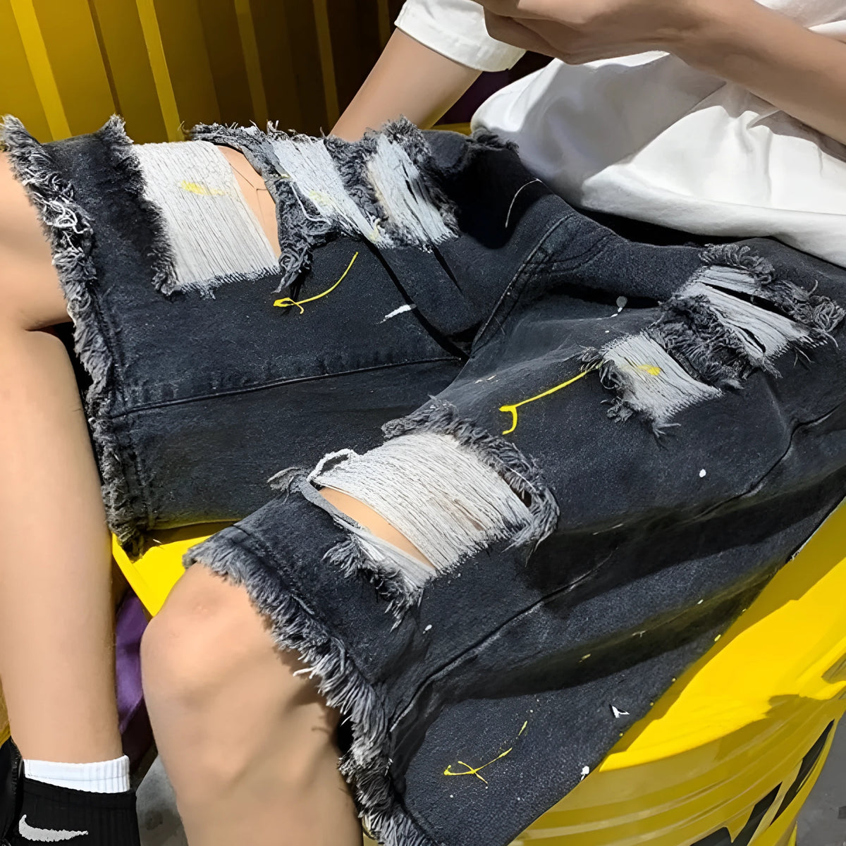 Man wearing loose-fit light blue water-washed denim shorts with a fifth pants length, showing street style.