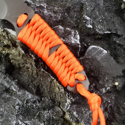 Straight-blade survival knife with a binding rope handle next to its black ABS plastic sheath.