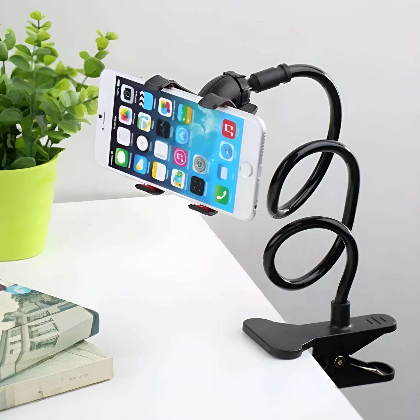 Black flexible long arm phone holder with V-clip holding a smartphone, bent over a bedside table