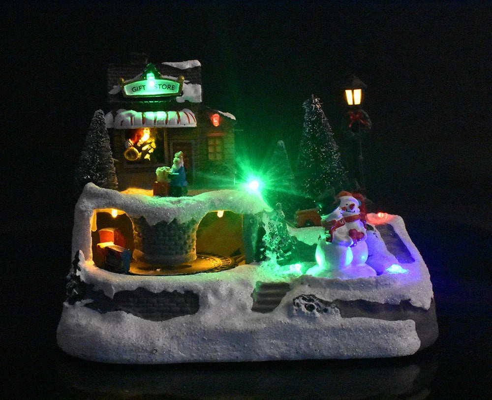Illuminated Christmas village house with rotating Santa, Snowman, and Christmas tree decorations and playing holiday music