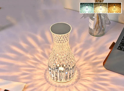Vase-shaped crystal table lamp with remote control on a bedside table, showing diamond-like glow and USB charging port.